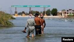 巴基斯坦南部信德省塞赫万地区的民众在被洪水淹没的高速公路上行走。(2022年9月16日)