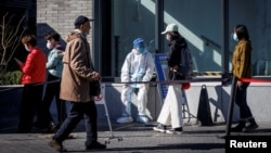 北京街头一名身穿防护服的大白坐在新冠核酸检测桌旁。(2022年10月23日)