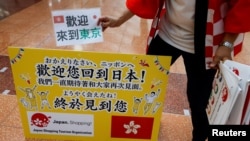 日本一家旅游公司的员工在羽田机场欢迎一个香港旅游团。(路透社2022年6月26日)