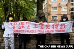 示威者在中国驻曼彻斯特领事馆外手持北京四通桥悬挂反习标语的横幅举行抗议。(2022年10月16日)