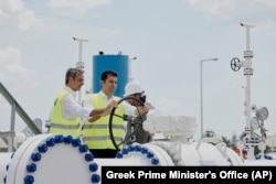 Greek Prime Minister Kyriakos Mitsotakis, left, and his Bulgarian counterpart Kiril Petkov, turn a valve during the inauguration of a gas pipeline in Komotini, Greece, July 8, 2022.