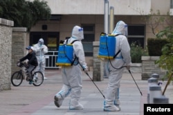 身穿防护服的防疫人员在北京一个被封的居民区喷洒消毒药水。(2022年11月9日)