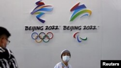 一名戴着口罩的妇女走过北京的国际服务贸易交易会悬挂的2022年冬季奥运会和冬季残奥会标识。(2021年9月3日)