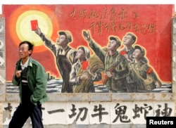 资料照:一名男子走过宁夏银川街头郊区的一处描写中国文革的宣传画。(2007年4月25日)