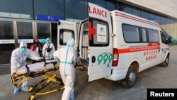 不断变种的新冠毒株,为2022北京冬奥会蒙上极大的不确定阴影。图为身穿防护服的红十字会救护人员在北京的一个媒体中心将一个担架送入救护车中。(路透社2022年1月7日)