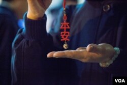 台北第二殡仪馆内的慈济义工在现场分发“平安”挂饰。(美国之音记者方正拍摄)