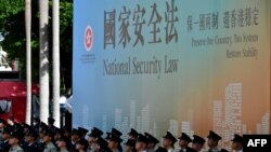 资料照:香港警察举行升旗仪式与他们背后的国安法宣传牌。(2020年7月1日)