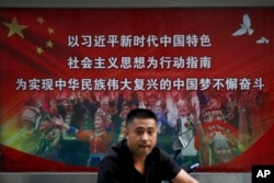 一名男子走过北京街头宣传习近平指示的各族人民大团结中国梦的广告牌。(20218年9月11日)