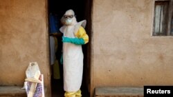 FILE - Health care workers enter a house where a baby suspected of dying of Ebola is, during the baby's funeral in Beni, North Kivu province, Democratic Republic of the Congo, Dec. 18, 2018.