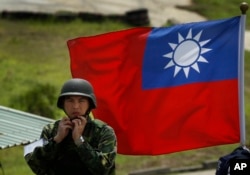 资料照:台湾旗帜前一名士兵整理自己的头盔。