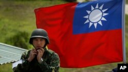 资料照:台湾旗帜前一名士兵整理自己的头盔。