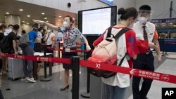 资料照:北京首都机场的工作人员检查旅客们的COVID-19测试结果