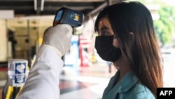 အပူချိန်တိုင်းတာခြင်းခံယူနေသည့် အမျိုးသမီးတဦး (သတင်းဓာတ်ပုံ - မတ် ၂၅၊ ၂၀၂၀)