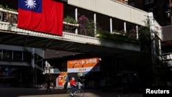 资料照片:一位男士在台北街头骑车。(2021年11月16日)