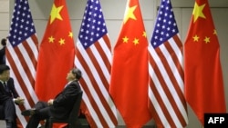 资料照:两名男子在大阪G20峰会期间会场摆放的美中国旗前聊天。(2019年6月29日)