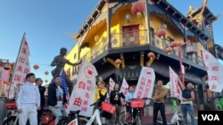 11月16日,骑行活动参与者在洛杉矶唐人街李小龙雕像前--美国之音 张木林 拍摄