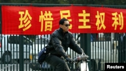 一名北京男子骑车从敦促市民积极参加地方选举的标语前路过。(资料照片)