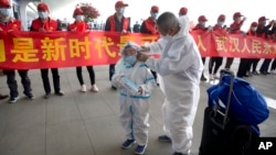 武汉解封,天河国际机场的旅客站在庆祝的标语横幅旁。(2020年4月8日)