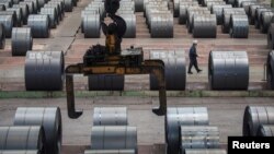 资料照:中国重庆钢铁厂一名工人走过钢卷存放地。(2018年8月6日)