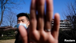 中国安全人员阻挡新闻摄影师拍摄世界卫生组织一个专家组在武汉的行踪(路透社2021年2月6日)