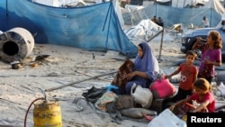 在加沙地带南部汗尤尼斯的 Al-Mawasi 地区,以色列袭击了一个为流离失所者提供庇护的帐篷营地,一名巴勒斯坦妇女在现场翻看儿童身边的物品。(2024年9月10日)