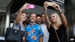 俄罗斯总理梅德维耶夫在参加东盟峰会后和俄罗斯与乌克兰游客合影(2015年11月22日)