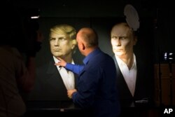 2016年11月9日,一名俄罗斯记者用手指指着川普的画像。右边是普京总统的画像。