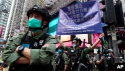 资料照片:香港警方在庆祝中国共产党建立中华人民共和国的节日期间在铜锣湾街向抗议者举出警告旗帜。(2020年10月1日)