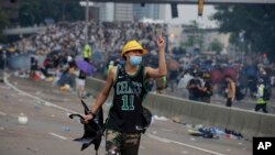 一名抗议香港逃犯条例修订的香港示威者向与抗议者发生冲突的防暴警察做手势。(2019年6月12日)