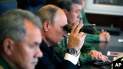 俄罗斯总统普京(中)国防部长绍伊古(左)俄罗斯武装部队总参谋长瓦列里·格拉西莫夫(右)观看军事演习。