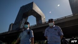 两名警察在北京街头巡逻,背景是中国中央电视台大楼。(2020年5月19日)