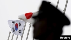 一名日本警察站在东京一家飘扬着日韩国旗、正在举行日韩关系正常化50周年庆祝仪式的酒店前执勤。(2015年6月22日)