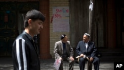 FILE - Ethnic Uighurs chat in an alley before they proceed for their Friday prayers near a mosque in Urumqi, China's northwestern region of Xinjiang.