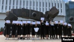 香港中文大学毕业生举起被中国拘押的12名港人的姓名牌子以示抗议。(2020年11月19日)