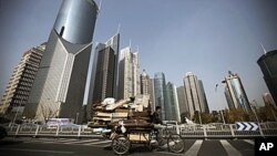 在上海的高楼大厦之间,一个男子骑着三轮车在收废品,贫富差距令人担忧