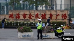 中国广东珠海全民健身广场发生一名凶犯驾车蓄意撞人重大恶性案件后,警察站在人们为死难者献的鲜花前。(2024年11月13日)