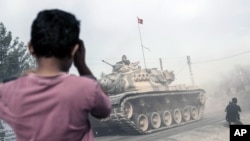 2016年8月25日,在土耳其,一个男孩看着土耳其军队坦克和装甲运输车跨过国界驶向叙利亚。