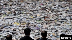 山西太原,人们看着满地的即将销毁的盗版影音光盘等出版品(2015年4月20日)