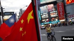 一名台湾妇女骑车从台北街头举行的台湾亲中国组织呼吁和平统一的一个集会前驶过。(2016年5月14日)