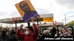 在明尼苏达州明尼阿波利斯市乔治·弗洛伊德广场,举着弗洛伊德画像的民众在听到前明尼苏达警察肖文被判有罪后发出欢呼。(2021年4月20日)