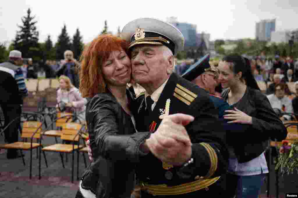 A woman dances with a veteran near the Defenders of Donbass monument during celebrations to mark Victory Day in Donetsk, eastern Ukraine May 9, 2014. Russian President Vladimir Putin praised the Soviet role in defeating fascism on Friday, the anniversary