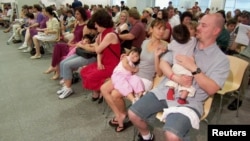 资料照:一对美国夫妇在中国广东省广州市的美国领事馆等待为他们新收养的中国孩子领取赴美签证。(2007年5月30日)