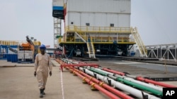 资料照片:中国海洋石油公司有限公司的承包商中海油田服务股份有限公司的一名乌干达工人走过艾伯特胡畔翠鸟油田钻井附近的管道。(2023年1月24日)