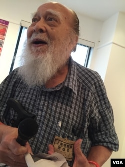 96岁的何天开老人展示文革劳改犯标识(2016年5月,美国之音方冰拍摄)。他因为拥有一张江青和唐纳结婚的杂志照片而在1972年被监禁,判决书说“何犯恶毒污蔑攻击我党的严重罪行经拘留后拒不认罪,态度恶劣,依法判处5年徒刑。”