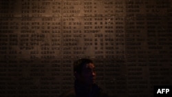 (资料照片)一名中国游客于2014年2月12日在南京大屠杀纪念馆参观日军战争罪行受害者名单。