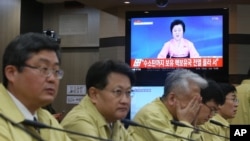 韩国外交部官员举行紧急会议,旁边的电视播放着朝鲜宣布核试验的新闻(2016年1月6日)