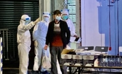 多名穿着全套保护衣的工作人员指示油麻地突袭封锁区内的居民接受强制病毒检测。 (美国之音/汤惠芸)