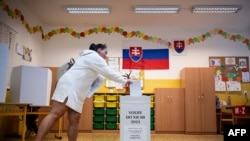 2023 年 9 月 30 日,斯洛伐克的布拉迪斯拉发市中心举行斯洛伐克议会选举,一名选民在投票站将选票投进投票箱中。