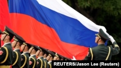 资料照:中国解放军仪仗队手举俄罗斯国旗接受俄罗斯总统普京的检阅。(2018年6月8日)