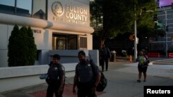 在佐治亚州大陪审团对美国前总统特朗普及18名盟友提出起诉后,人们从亚特兰大的刘易斯·R·斯莱顿法院外走过。(2023年8月15日)